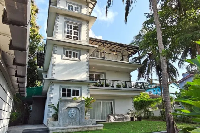 Front elevation of the three-storey villa with landscaped gardens, paved driveway, and private balconies