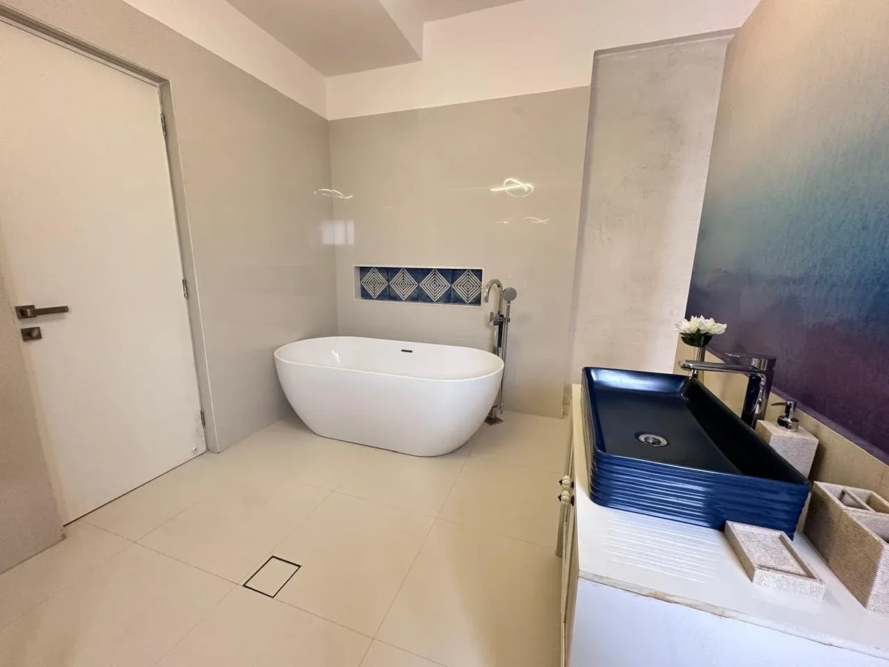 Master en-suite bathroom featuring freestanding soaking tub, vessel sink vanity, and designer tile alcove