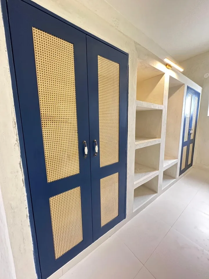 Dressing area with custom cane-panelled wardrobes and illuminated display shelving