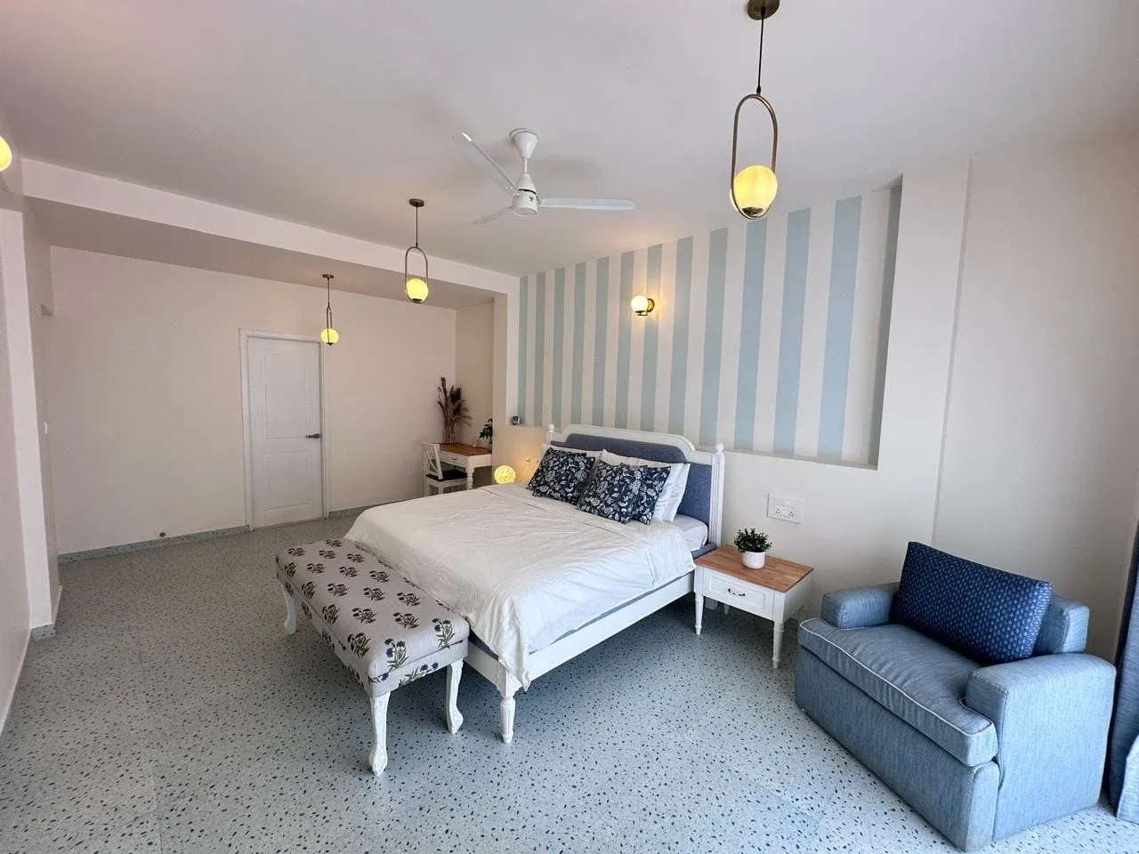 Second bedroom suite with striped feature wall, king bed, study workstation, and terrazzo flooring