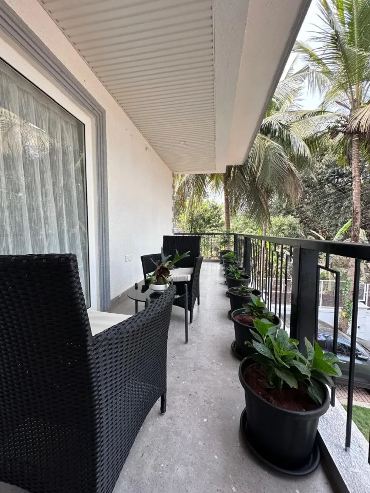 Deep covered terrace balcony with outdoor wicker seating and panoramic tropical greenery views