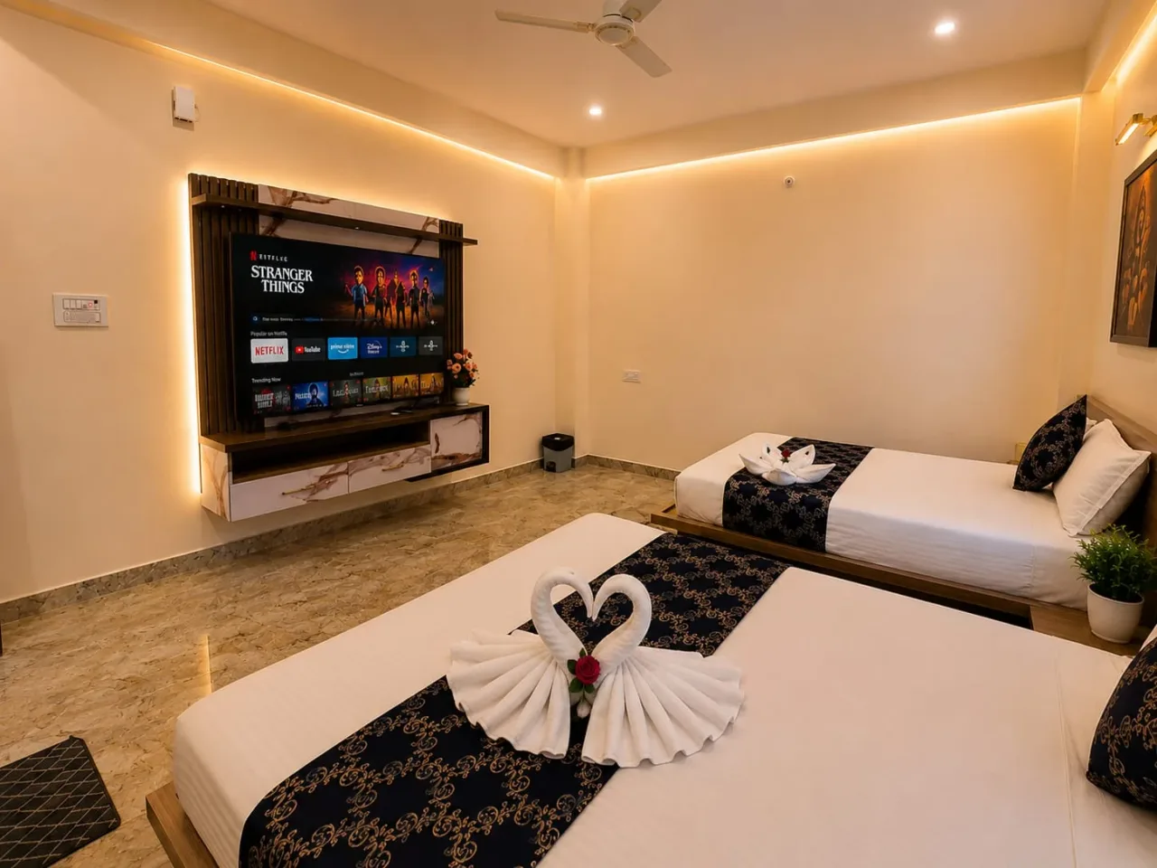 Full guest room layout showing twin beds, smart TV running streaming apps, cove lighting, and bedside planters