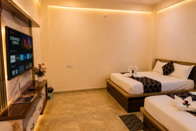 Air-conditioned guest bedroom suite with twin queen beds, polished marble flooring, smart LED TV console, and decorative swan towel art