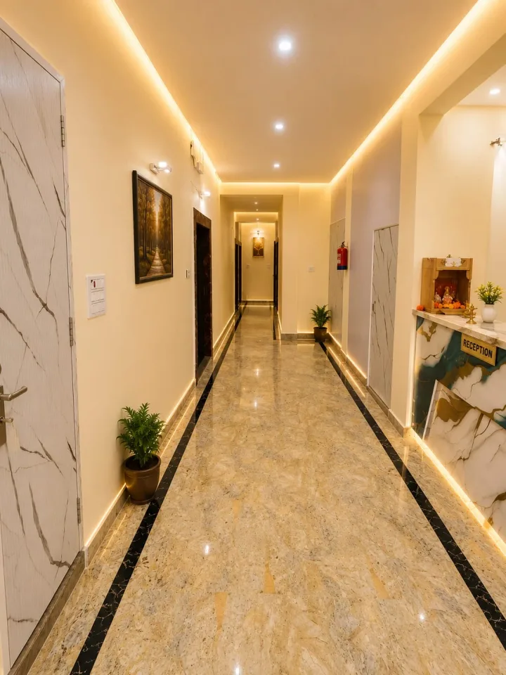 Bright reception corridor with polished marble-look flooring, brass front desk, mandir, and cove LED lighting