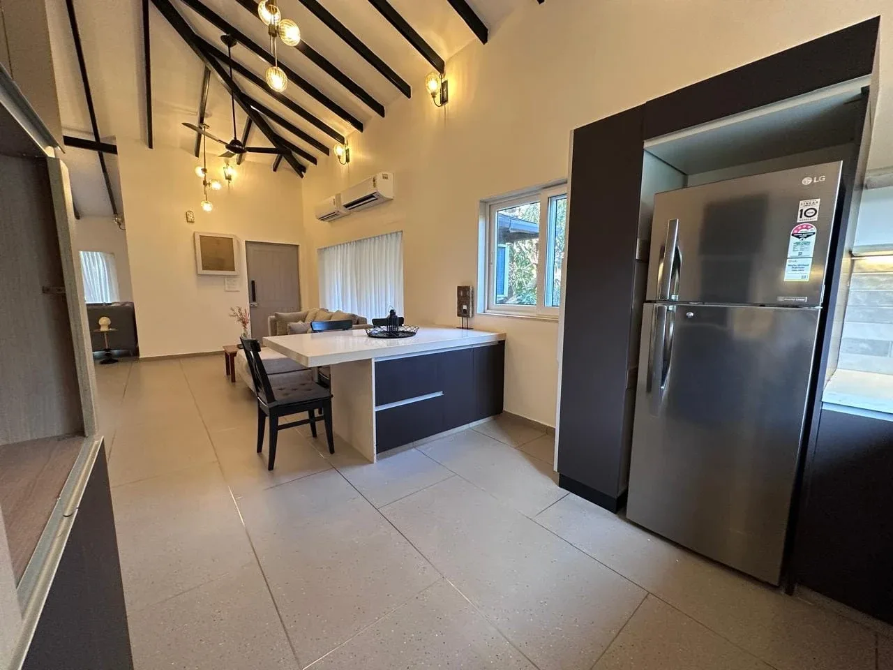 Fitted kitchen with solid quartz breakfast island, large stainless steel refrigerator, and custom cabinetry