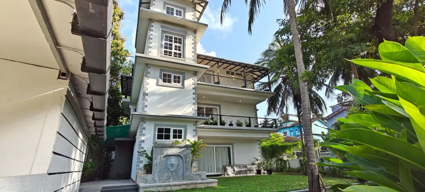 Three-storey villa exterior facade featuring manicured lawn, lion fountain, and private balconies