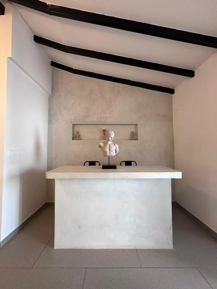 Microcement bar and study niche with recessed display shelving and exposed timber rafters