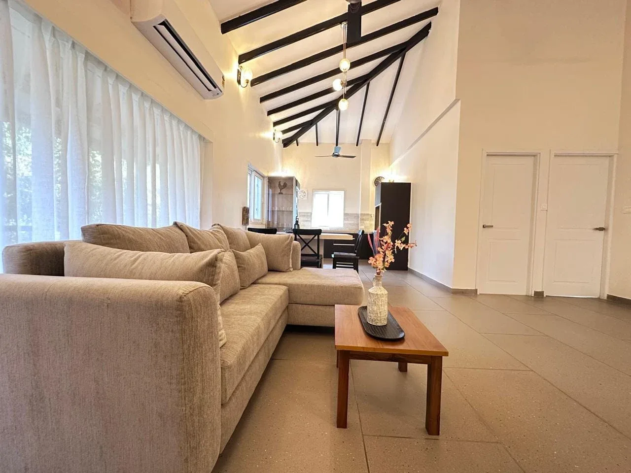 Spacious open-plan living room with vaulted cathedral timber ceiling, L-shaped sectional sofa, and pendant lighting