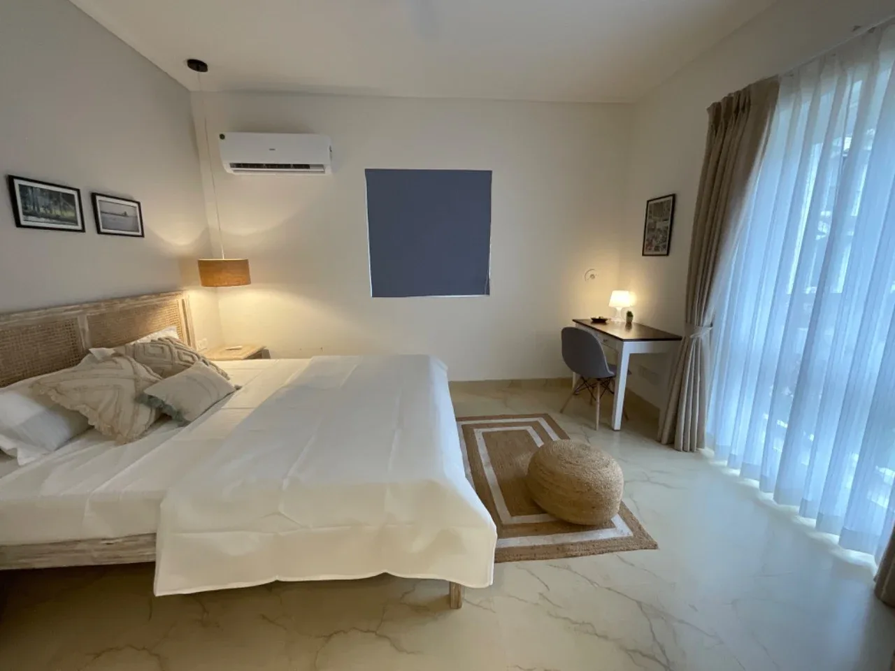 Spacious ground-floor bedroom suite with reading lamp, jute rug, and pouf