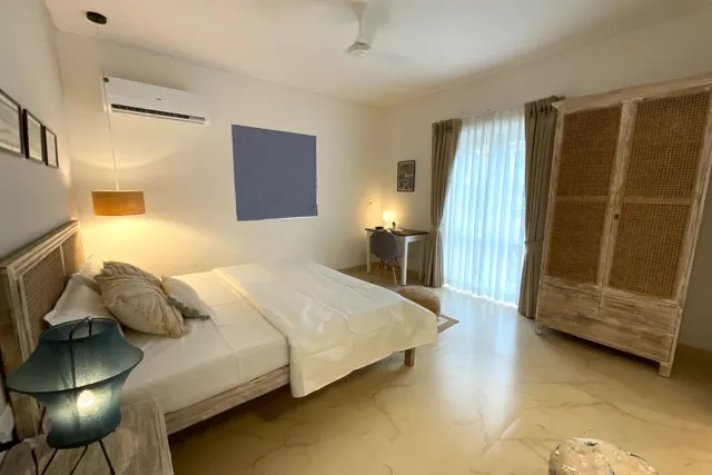 Ground-floor bedroom suite with study desk, cane wardrobe, and floor-to-ceiling balcony doors