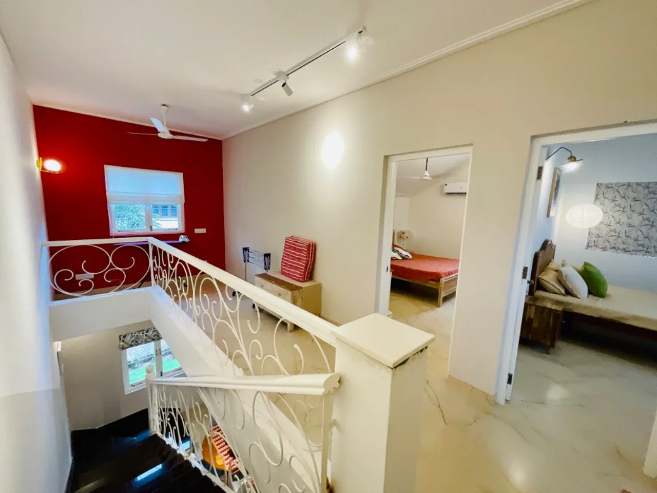 Upper floor landing with decorative white wrought-iron staircase railing and red feature wall