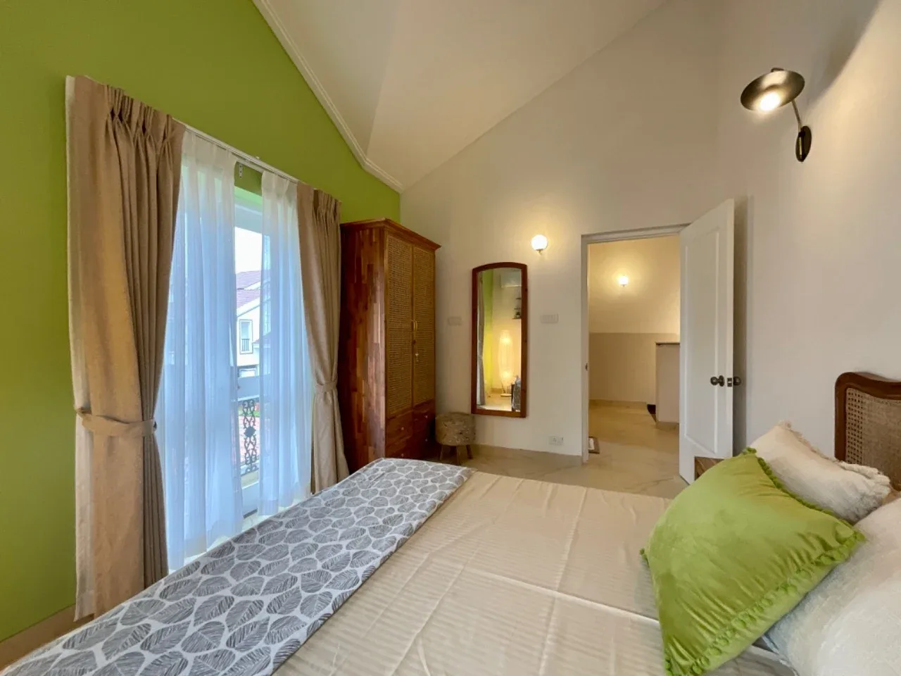 Second bedroom with teak and cane wardrobe, full-length mirror, and balcony access