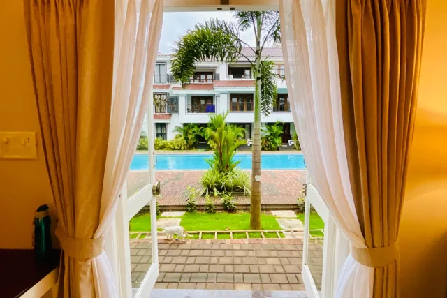 View through French doors across the private patio and lawn towards the resort-style swimming pool