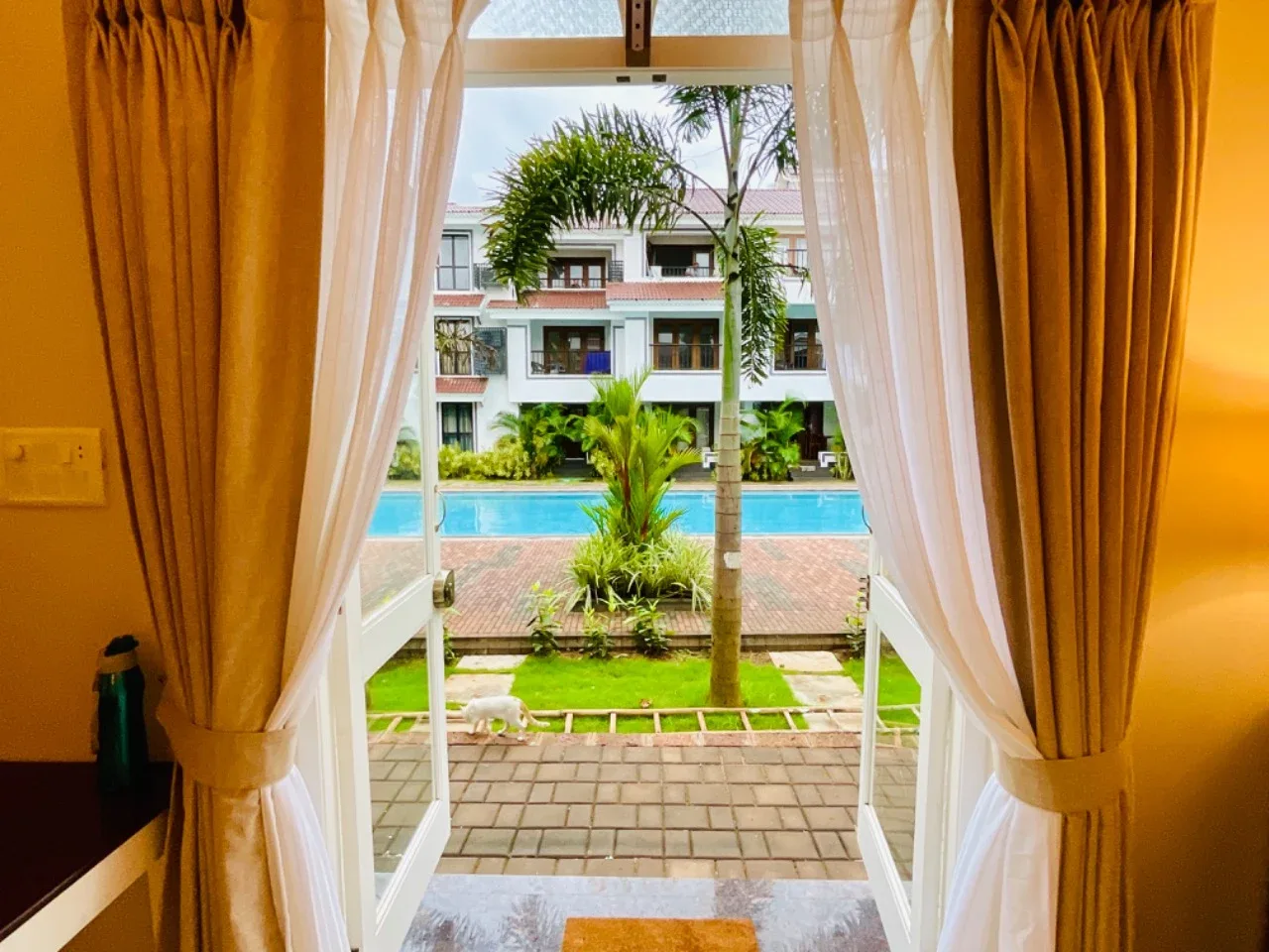 View through French doors across the private patio and lawn towards the resort-style swimming pool